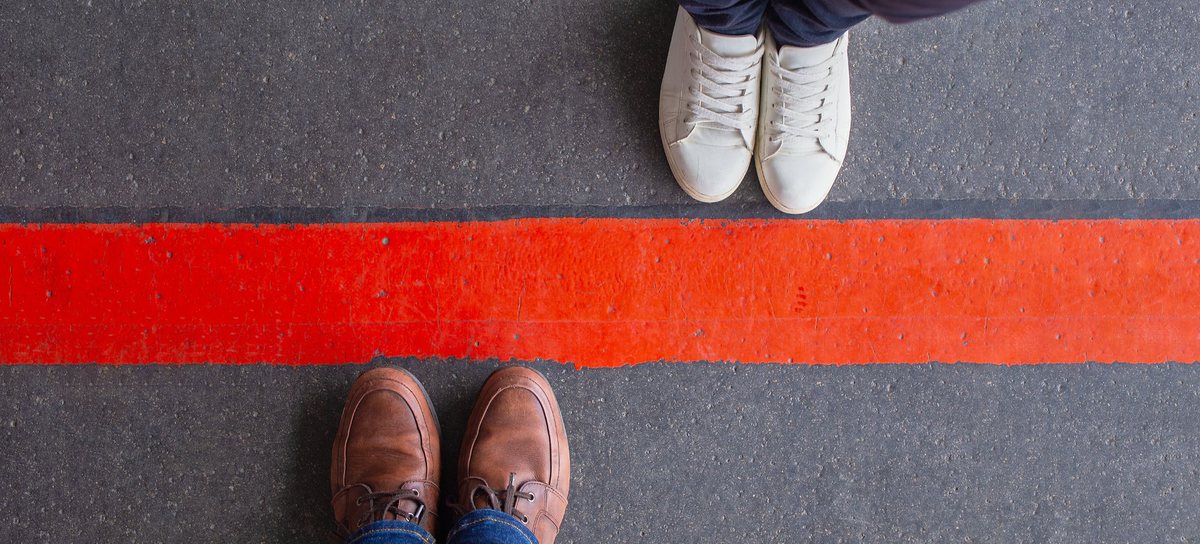Two people standing on opposite sides of a red line on the asphalt